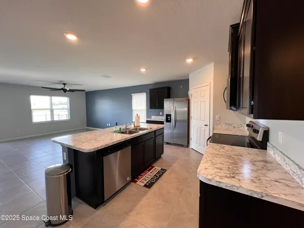a kitchen with granite countertop kitchen island stainless steel appliances a sink stove and refrigerator