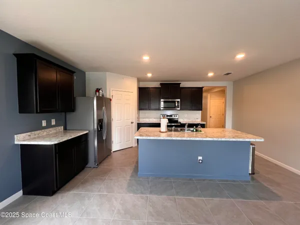 a living room with stainless steel appliances kitchen island furniture a flat screen tv and a kitchen view