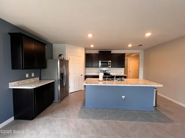 a living room with stainless steel appliances kitchen island furniture a flat screen tv and a kitchen view