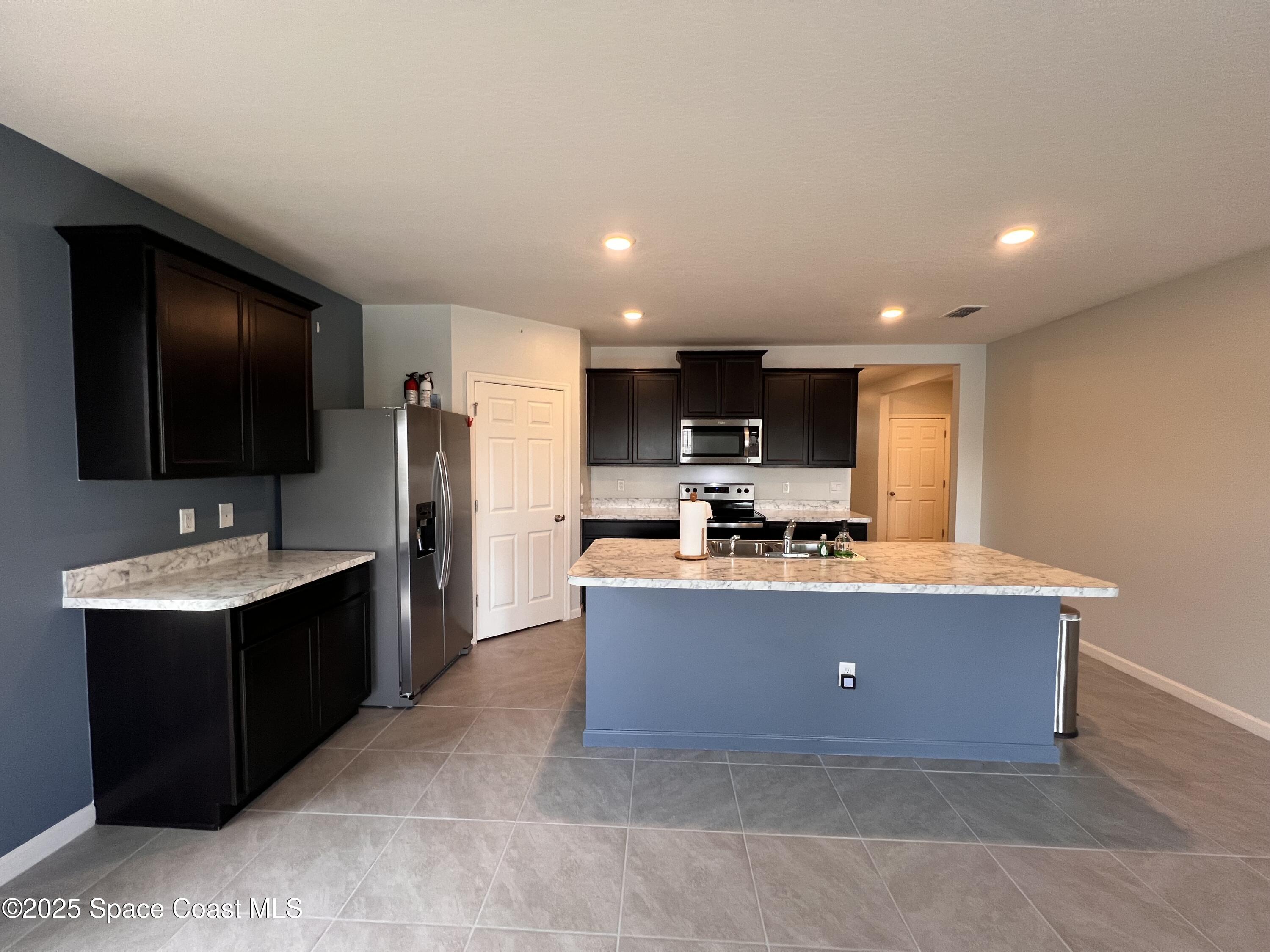 4871 Talbot Boulevard Cocoa, FL 32926 - Photo 16 of 25 a living room with stainless steel appliances kitchen island furniture a flat screen tv and a kitchen view