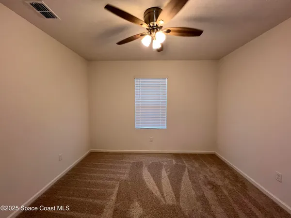 an empty room with a window and a fan