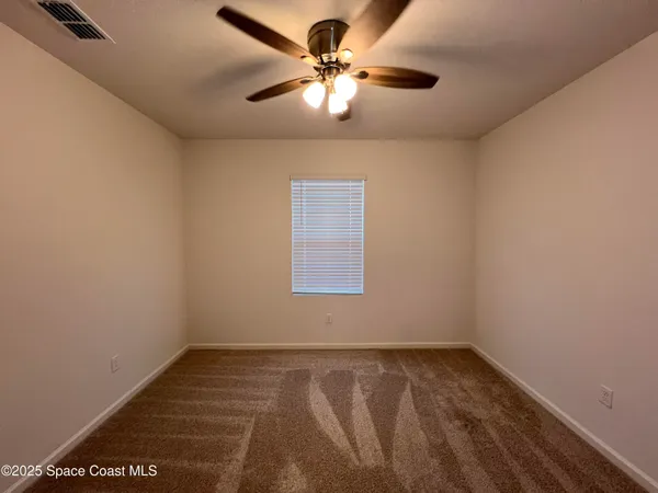 an empty room with a window and a ceiling fan