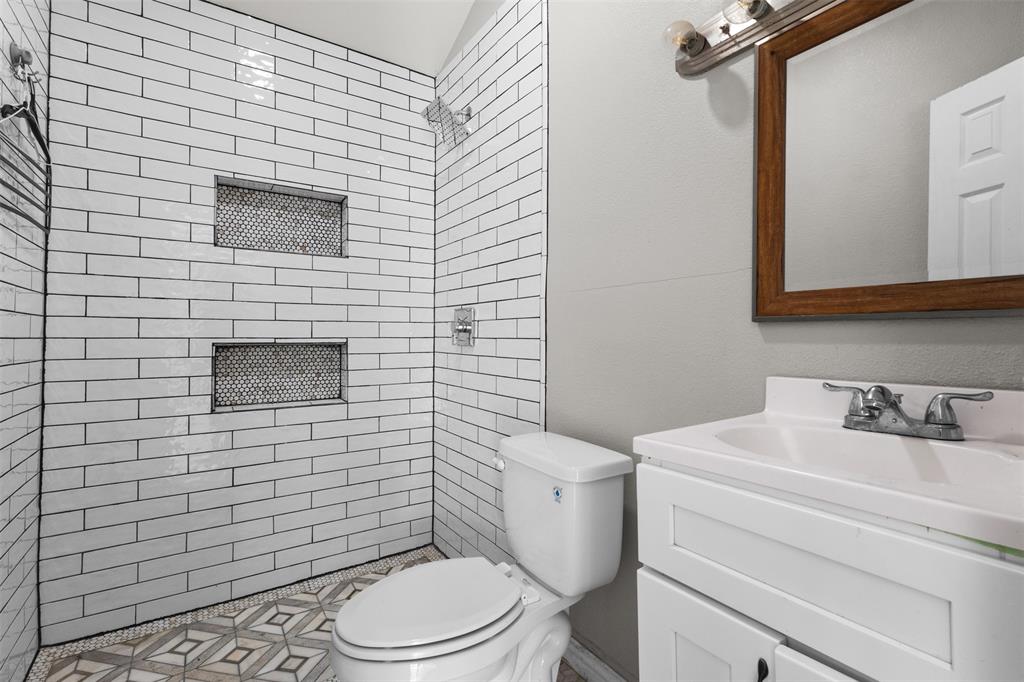 145 Lawson Road Mesquite, TX 75181 - Photo 23 of 31 a bathroom with a toilet a sink and mirror