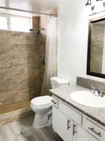 a bathroom with a granite countertop sink toilet and shower