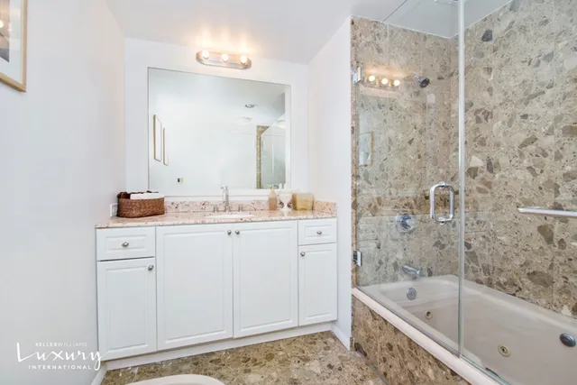 a bathroom with a granite countertop sink a mirror a bathtub and shower