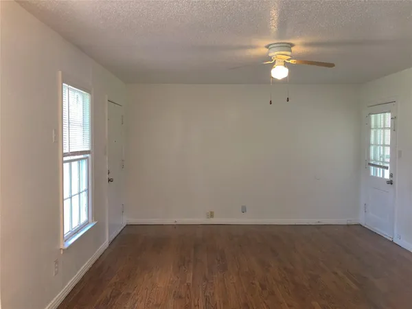an empty room with windows and chandelier fan