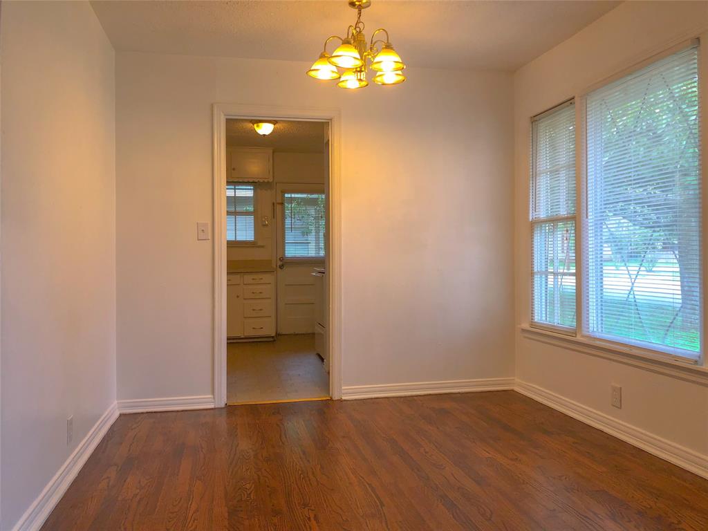 527 Euclid Street Cleburne, TX 76033 - Photo 4 of 8 Empty room featuring dark tile flooring and an inviting chandelier