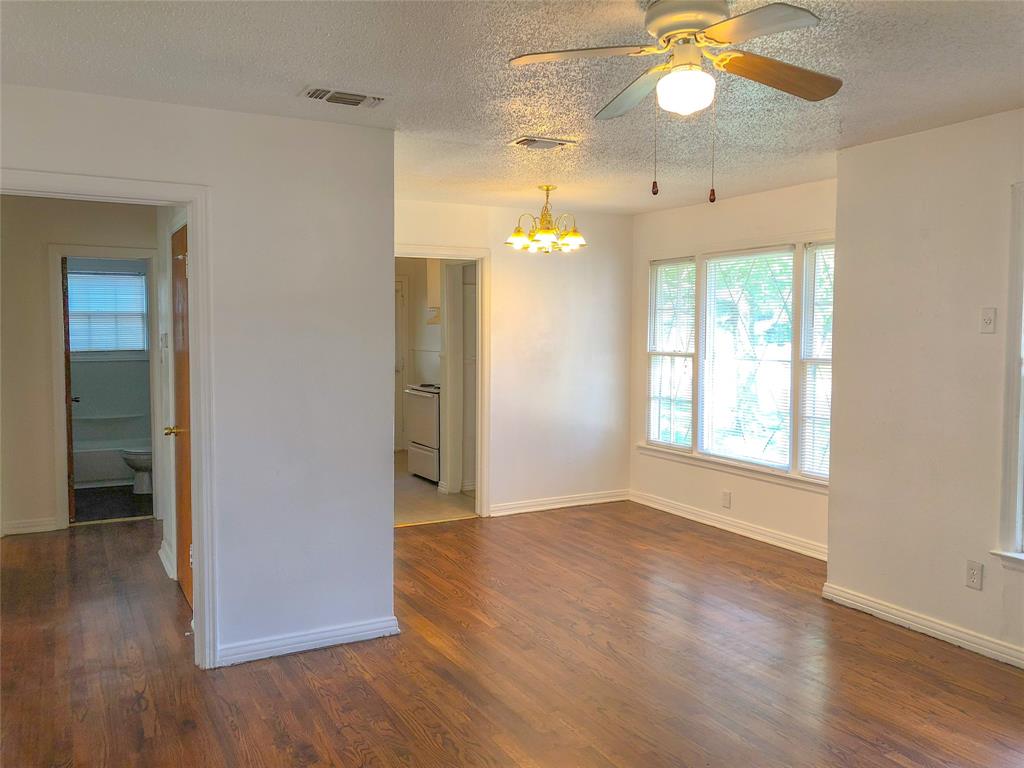 527 Euclid Street Cleburne, TX 76033 - Photo 5 of 8 Spare room featuring dark hardwood / wood-style floors, ceiling fan with notable chandelier, and a textured ceiling