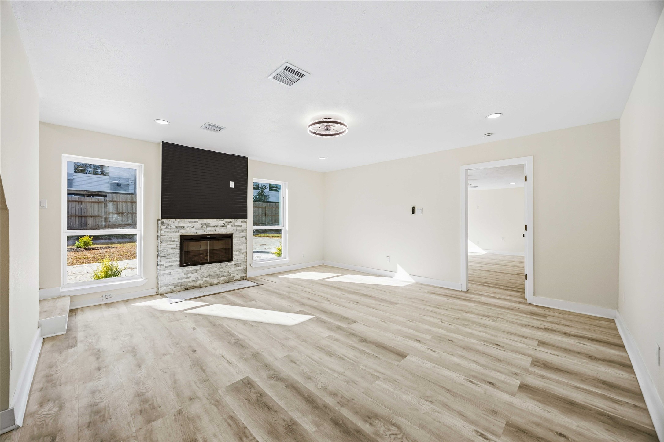 18234 Atkinson Lane Conroe, TX 77384 - Photo 4 of 30 The living room features a bold fireplace and oversized windows that let sunlight bounce across the seamless new vinyl plank flooring.