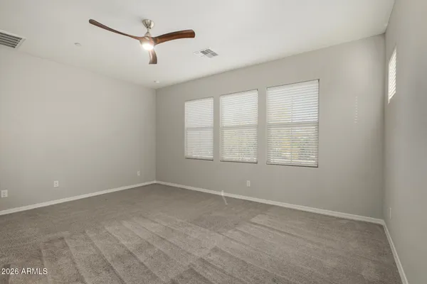 an empty room with ceiling fan and windows