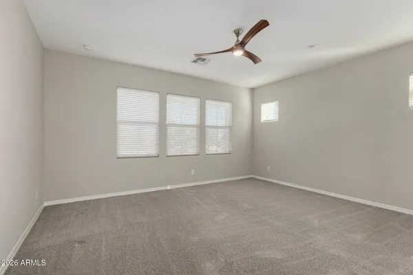 an empty room with ceiling fan and windows