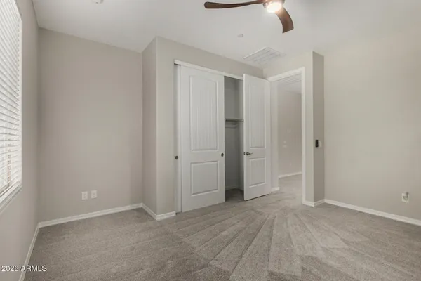 an empty room with ceiling fan and window