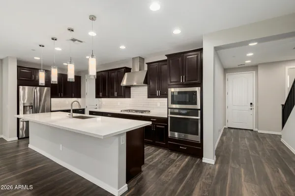 a large kitchen with a large counter top a sink stainless steel appliances and cabinets