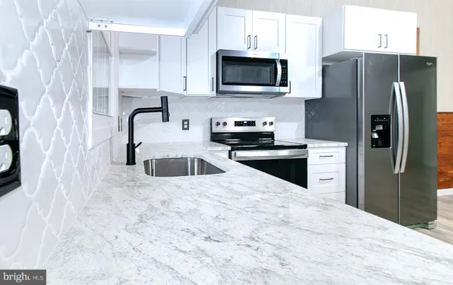a kitchen with granite countertop a refrigerator stove and microwave