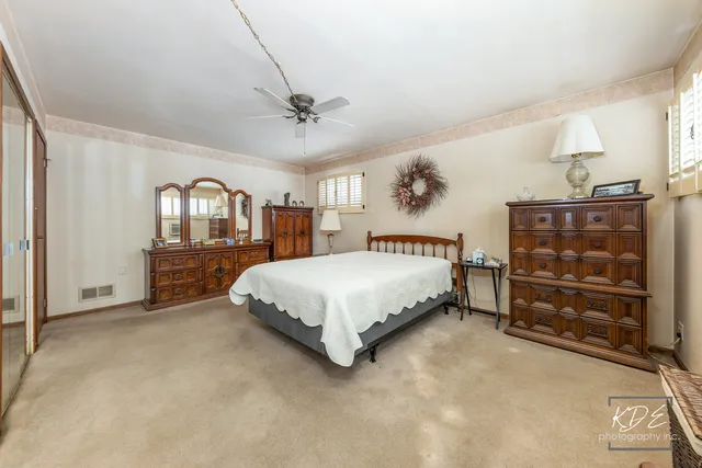 a spacious bedroom with a bed a dresser and shelf with wooden floor