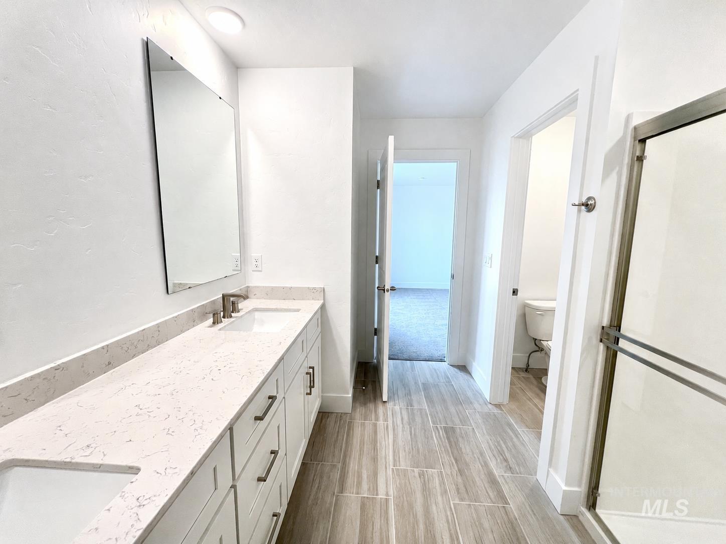 8098 West Fern Street Eagle, ID 83616 - Photo 18 of 22 Spacious bathroom featuring a dual vanity with undermount sinks, stone-finish countertops, and white shaker cabinetry