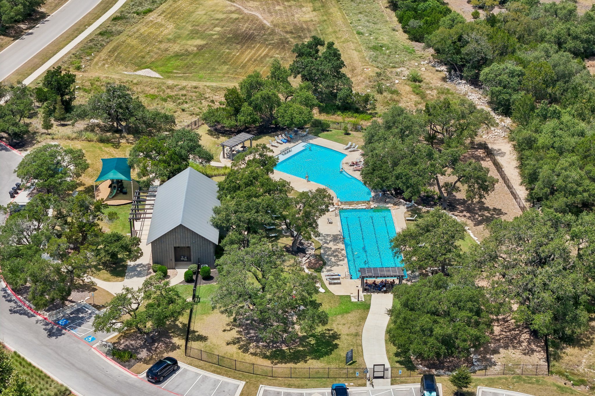 1705 Parten Rnch Parkway Austin, TX 78737 - Photo 38 of 39 An aerial perspective reveals the vibrant community pool and clubhouse, nestled among verdant trees and open green spaces.