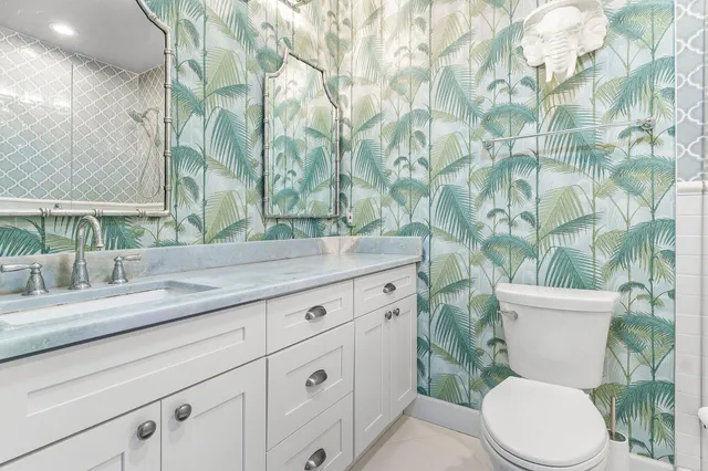 a bathroom with a granite countertop toilet sink and mirror