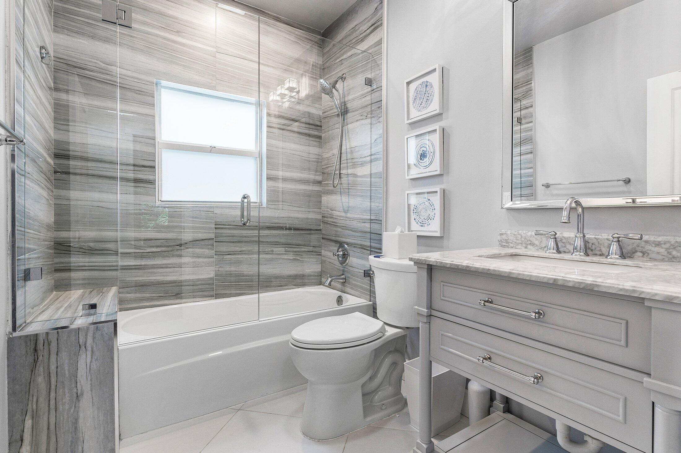 414 Northeast 7th Avenue Delray Beach, FL 33483 - Photo 19 of 29 a bathroom with a granite countertop toilet a sink and a bathtub