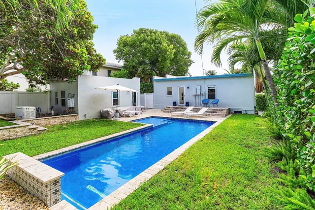 a view of pool with lawn chairs and plants