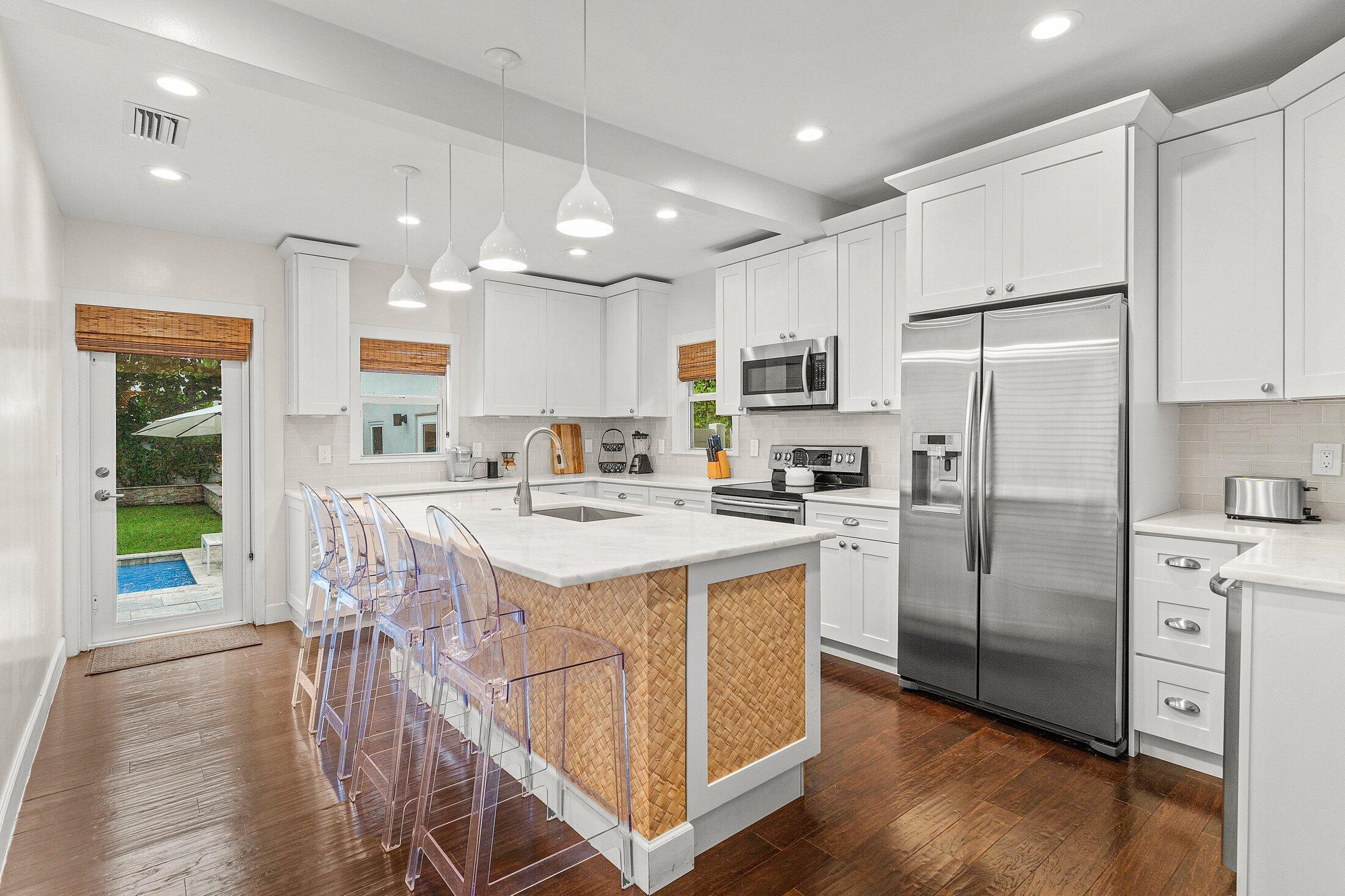 414 Northeast 7th Avenue Delray Beach, FL 33483 - Photo 3 of 29 a kitchen with kitchen island a stove a sink a refrigerator and a dining table with wooden floor