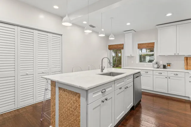 a kitchen with a sink dishwasher and white cabinets with wooden floor