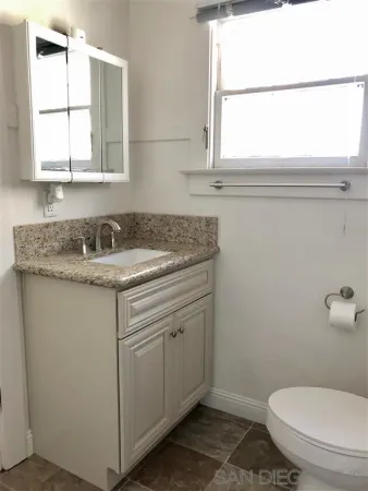 a bathroom with a granite countertop toilet sink and mirror