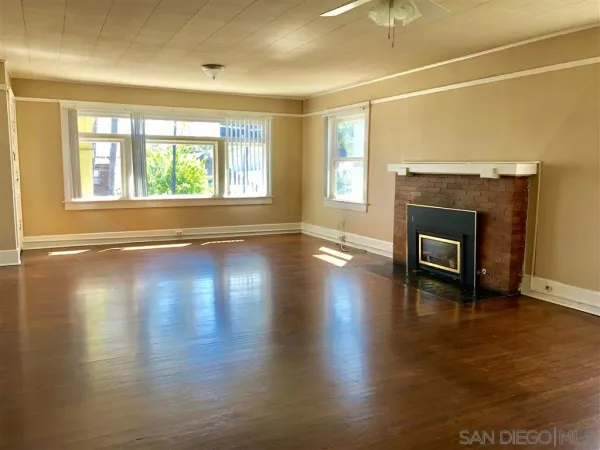 an empty room with floor to ceiling windows and fireplace