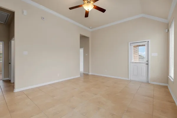 a view of an empty room with chandelier fan