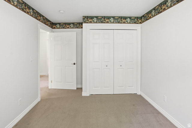 2190 750 West Perry, UT 84302 - Photo 26 of 42 Neutral tone walls with a decorative wallpaper border, carpet flooring, a white paneled door, and bi-fold closet doors