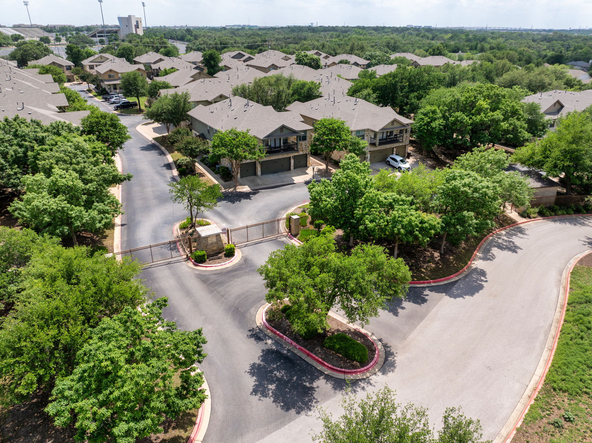 14815 Avery Ranch Boulevard, Unit 1401 Austin, TX 78717 - Photo 30 of 38 Gated community entrance with asphalt roads, mature trees, and structured landscaping