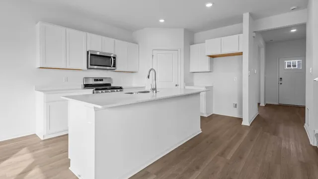 a kitchen with stainless steel appliances a wooden floor a stove a sink and a refrigerator