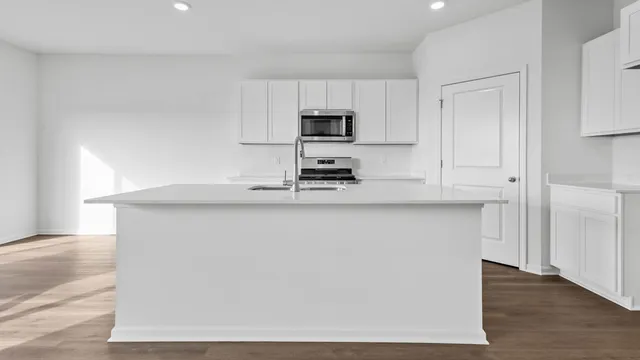 a kitchen with kitchen island a sink a stove a microwave and wooden floor