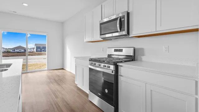 a kitchen with stainless steel appliances granite countertop a stove a microwave and a white cabinets