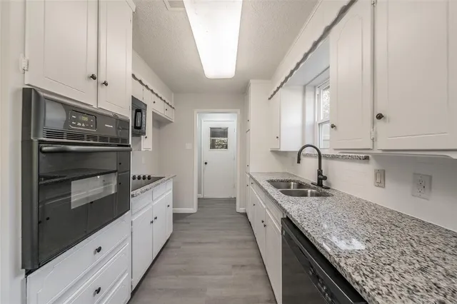 a kitchen with stainless steel appliances granite countertop a sink and dishwasher a stove top oven with wooden floor