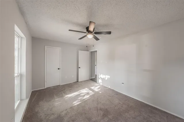 an empty room with ceiling fan and window
