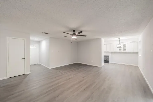 an empty room with wooden floor ceiling fan and windows