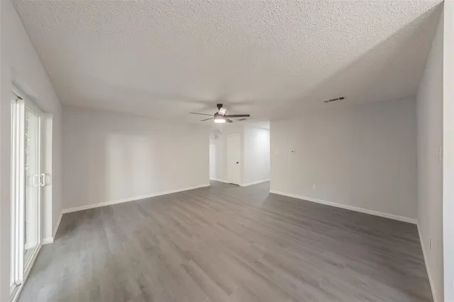 an empty room with wooden floor and fan