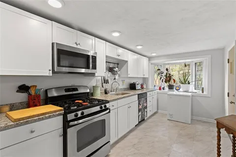 a kitchen with granite countertop a stove top oven sink and cabinets