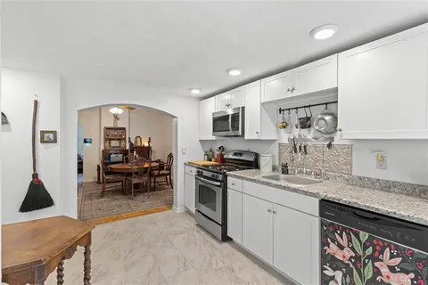 a kitchen with stainless steel appliances granite countertop a stove top oven a sink a dining table and chairs