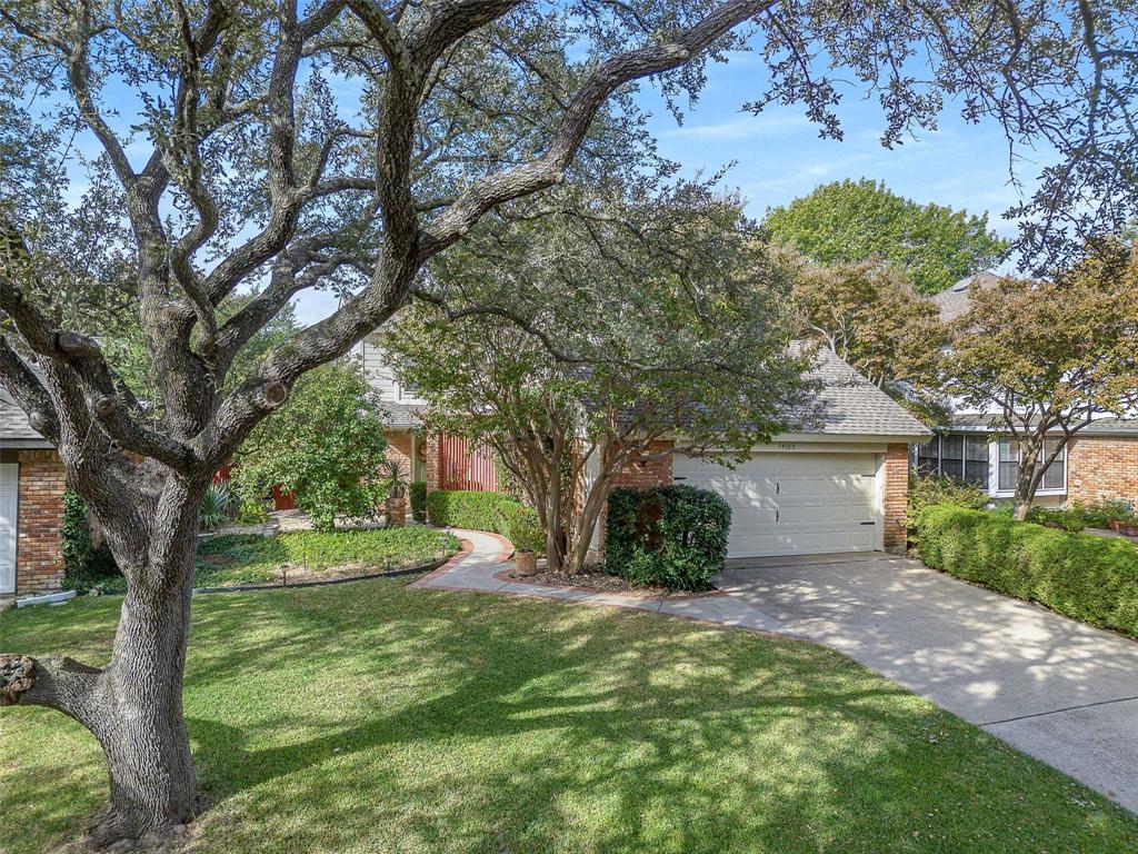 14683 Plage Lane Addison, TX 75001 - Photo 21 of 39 View of property hidden behind natural elements featuring brick siding, concrete driveway, a front yard, a garage, and a shingled roof