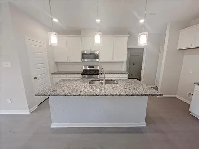 a kitchen with kitchen island granite countertop counter top space a sink stainless steel appliances and cabinets