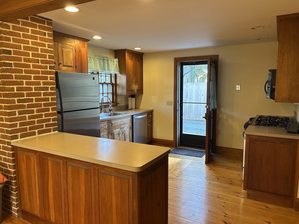 33 Woodland Street, Unit 1 Newburyport, MA 01950 - Photo 2 of 11 a kitchen with stainless steel appliances kitchen island granite countertop a table and chairs