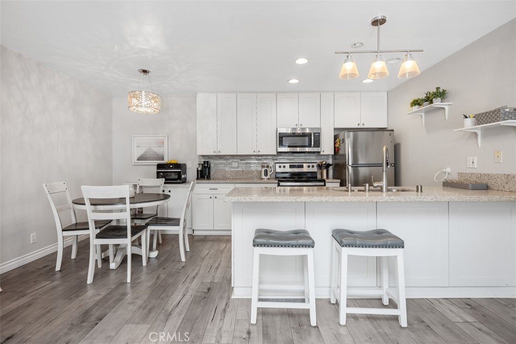21981 Rimhurst Drive, Unit P160 Lake Forest, CA 92630 - Photo 12 of 35 a kitchen with kitchen island granite countertop a dining table chairs wooden floors and white stainless steel appliances