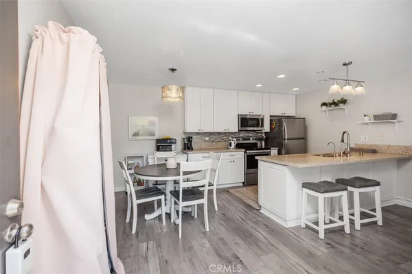 a kitchen with a table chairs a sink dishwasher a refrigerator and cabinets with wooden floor