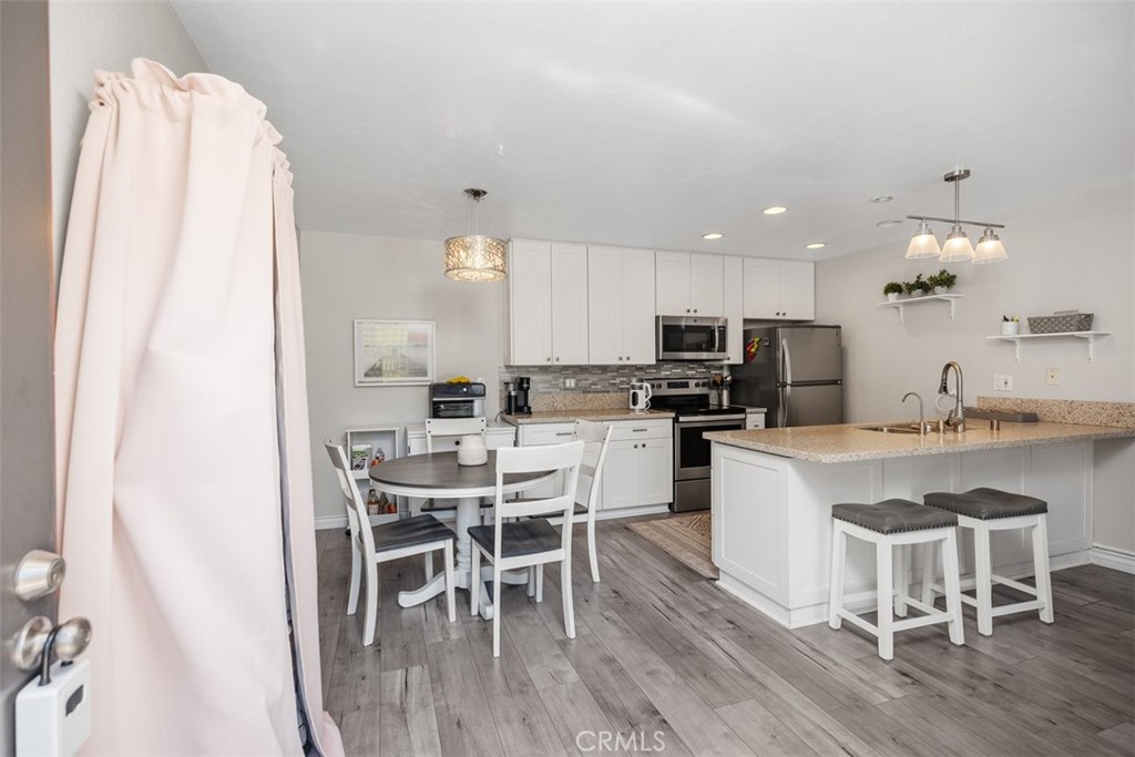 21981 Rimhurst Drive, Unit P160 Lake Forest, CA 92630 - Photo 7 of 35 a kitchen with a table chairs a sink dishwasher a refrigerator and cabinets with wooden floor