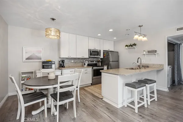 a kitchen with a dining table chairs stainless steel appliances and cabinets