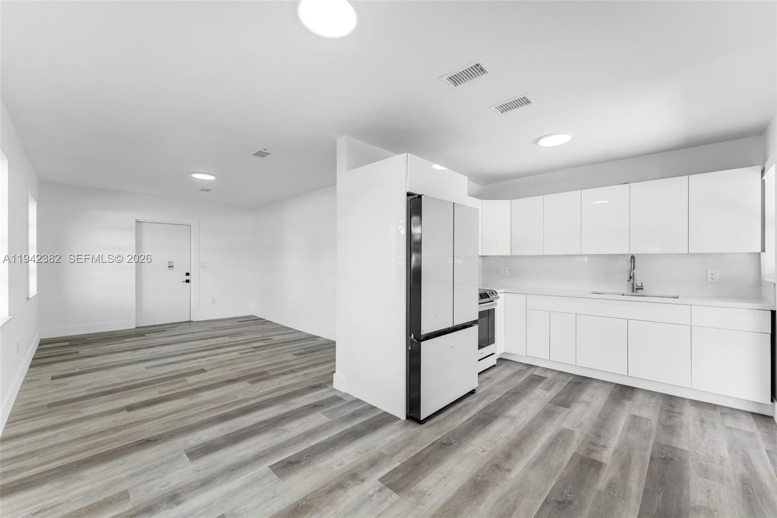 358 Pine Court Miami Springs, FL 33166 - Photo 6 of 24 a view of a kitchen with white cabinets and wooden floor