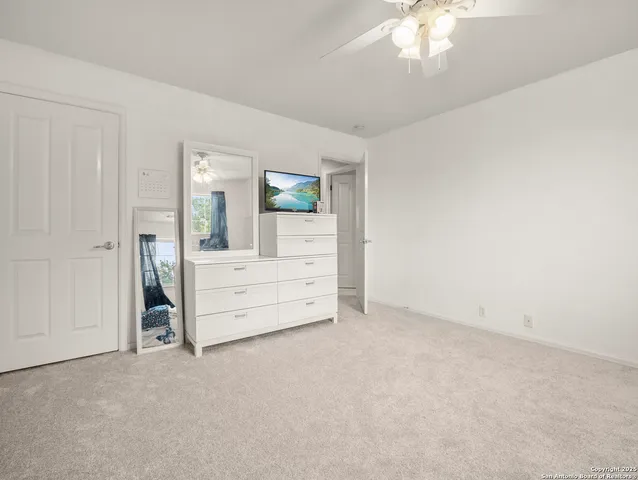 an empty room with chandelier fan and windows