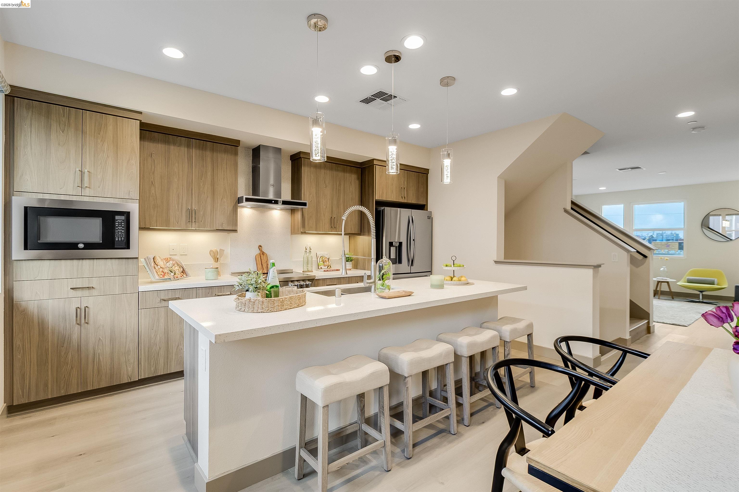 Contemporary kitchen featuring wood-finish cabinetry, stainless steel appliances, and a central island with a solid surface countertop